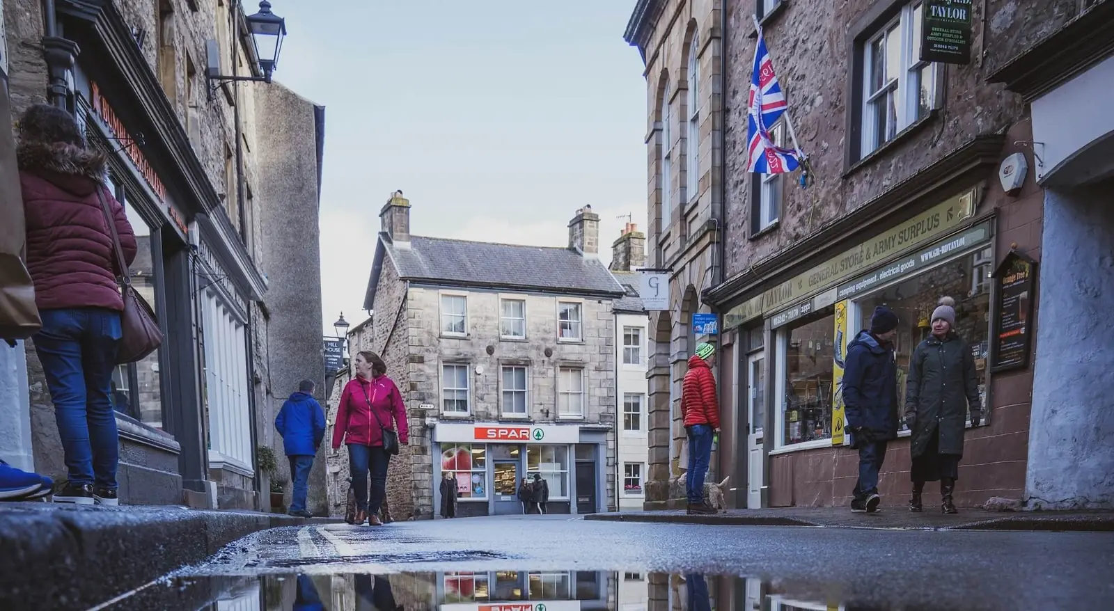 Shoppers walking past stone-built shops in Kirkby Lonsdale town centre